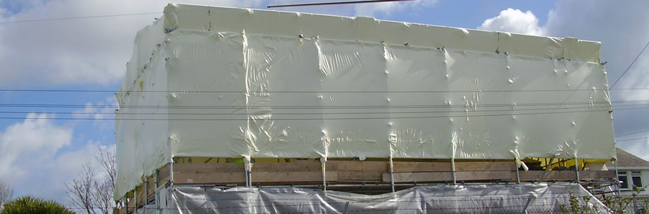 Photo of building with scaffolding and shrink wrap encapsulation in place protecting the structure